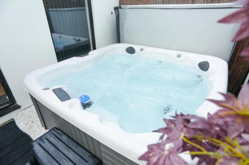 a jacuzzi tub sitting on a balcony with flowers at The Broadway Beach House with Hot tub in Kent