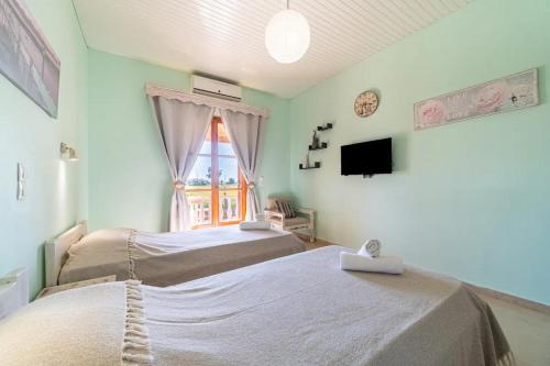 um quarto com duas camas e uma televisão e uma janela em natura studios superior almyros em Praia de Almiros