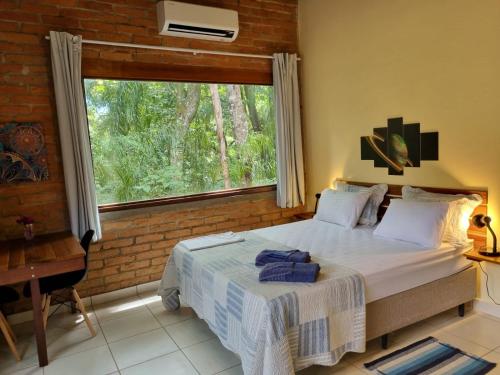 ein Schlafzimmer mit einem Bett und einem großen Fenster in der Unterkunft Contempla Joanópolis in Joanópolis