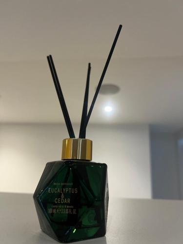 a green bottle with sticks in it on a table at London Heathrow Airport Apartment Voyager House Terminal 12345 - EV electric and Parking available in New Bedfont