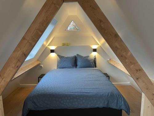 ein Schlafzimmer mit einem blauen Bett im Dachgeschoss in der Unterkunft Cottage Guest House in Wassenaar in Wassenaar