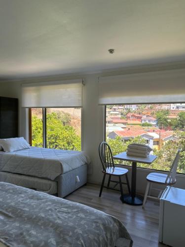 a bedroom with two beds and a table and a window at Hotel Boutique & Spa Puerto Natura in Valparaíso