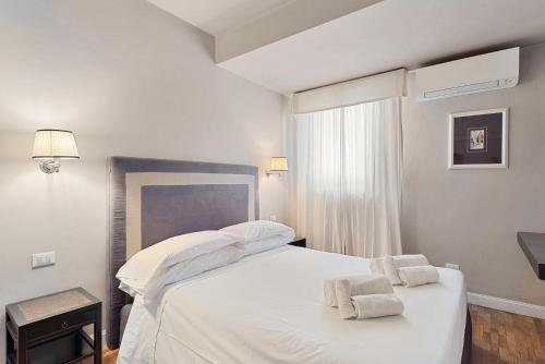 1 dormitorio con 1 cama blanca y 2 toallas en Tornabuoni Living - Luxury Apartments Collection, en Florencia