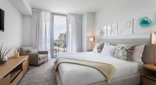 um quarto branco com uma cama grande e uma cadeira em Beachwalk Resort Residence em Hollywood