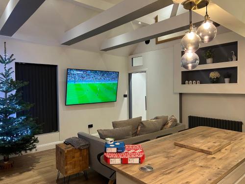 a living room with a christmas tree and a tv on the wall at The Broadway Beach House with Hot tub in Kent