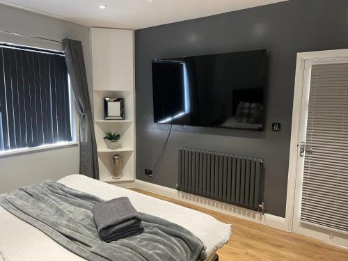 a bedroom with a bed with a flat screen tv on the wall at The Broadway Beach House with Hot tub in Kent