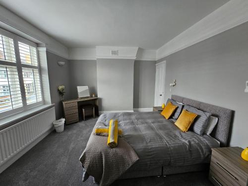 a bedroom with a large bed with yellow pillows at Knighton Villa in Leicester