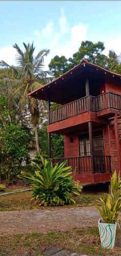 a red house with a balcony and a palm tree at Eco Cabanas Marakolliya in Tangalle
