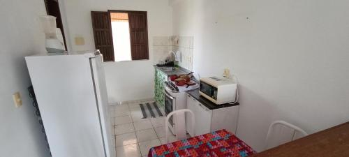 uma pequena cozinha com frigorífico e micro-ondas em Casa 2/4 em Itacimirim - Beira do Rio Pojuca em Camaçari