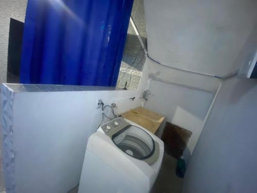 a small bathroom with a toilet with a blue curtain at Casa Geminada in Contagem