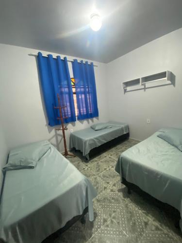 a room with two beds and a blue curtain at Casa Geminada in Contagem