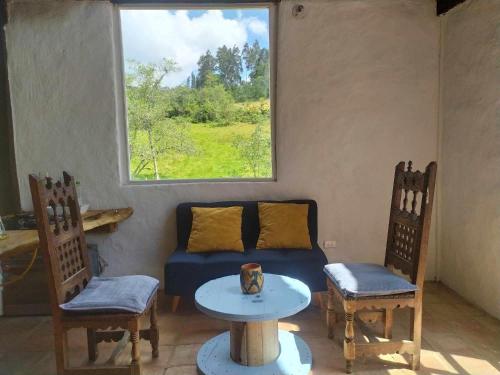 um quarto com um sofá e duas cadeiras e uma mesa em El chalet de Agnes em Villa de Leyva