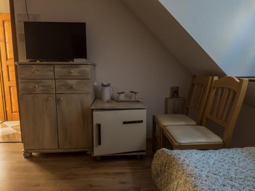 a bedroom with a dresser with a tv and a chair at Edvy Malom Apartmanok Pápa in Pápa