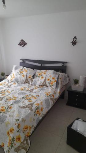 a bed with a floral comforter in a bedroom at El descanso in Bogotá