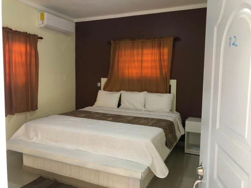 um quarto com uma cama branca e uma janela laranja em Diosamar Hotel y Suites em Santo Domingo