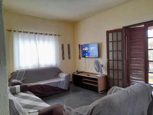 a bedroom with two beds and a tv on the wall at Casa em Cabo Frio in Cabo Frio