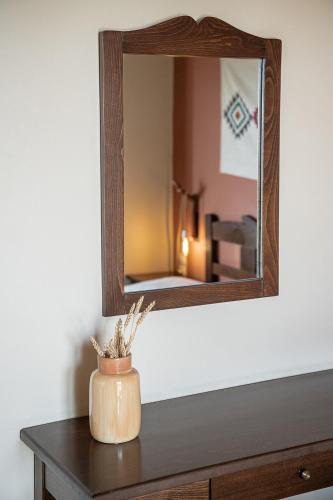 a mirror on a wall above a table with a vase at Earino in Kato Asites