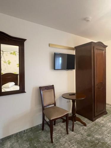 a room with a table and a chair and a cabinet at Pensiune Premier in Doctor Petru Groza