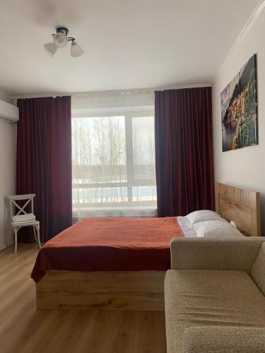 a bedroom with a bed and a couch and a window at Апартаменты Promenade Burabay in Borovoye