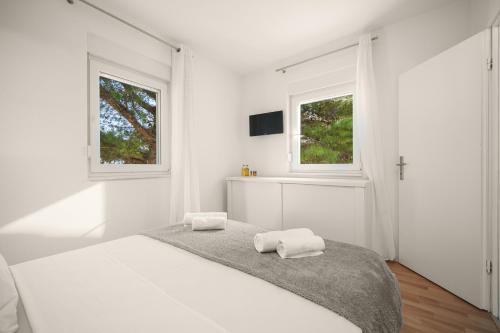 a white bedroom with a bed and two windows at Villa Pearl in Tribunj