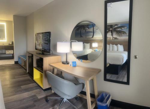 a hotel room with a desk with a bed and a mirror at Days Inn by Wyndham Port Charlotte Town Center in Port Charlotte