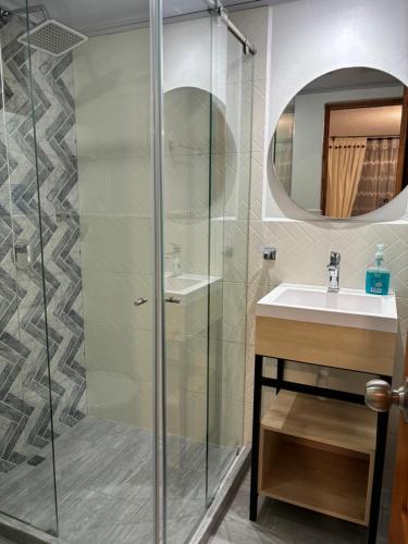 y baño con ducha acristalada y lavamanos. en Merak Hostel, en Villa de Leyva