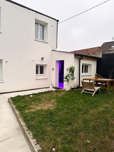 a white house with a purple door and a picnic table at L'Oasis Étoilée in Chelles