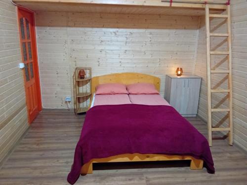 Un dormitorio con una cama con una manta morada. en Luna de miere en Cinciş