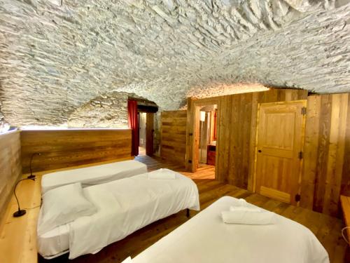 a bedroom with two beds and a stone ceiling at La Mizoùn de Marguerito - Appartamento Ginestra in Acceglio