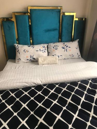 Una cama con cabecero azul y almohadas. en VICTOR'S SERENE STAYS, en Nairobi