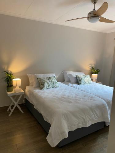 a bedroom with a large bed with a ceiling fan at De Vlei, Pretoria East in Pretoria