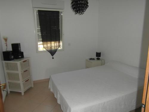 une chambre blanche avec un lit et une fenêtre dans l'établissement Résidence les Eucalyptus, à LʼÎle-Rousse