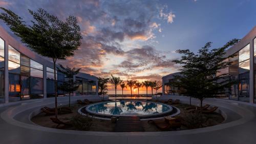 a building with a pool with a sunset in the background at iSea by the sea in Ninh Van Bay