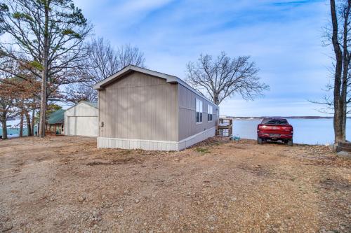 a barn with a red truck parked next to a body of water at Grand Lake Views Pet-Friendly Jay Getaway! in Jay