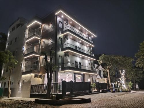 a tall building with lights on it at night at Emerald Suites in Greater Noida