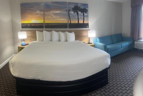 a hotel room with a large bed and a blue couch at Days Inn by Wyndham Port Charlotte Town Center in Port Charlotte