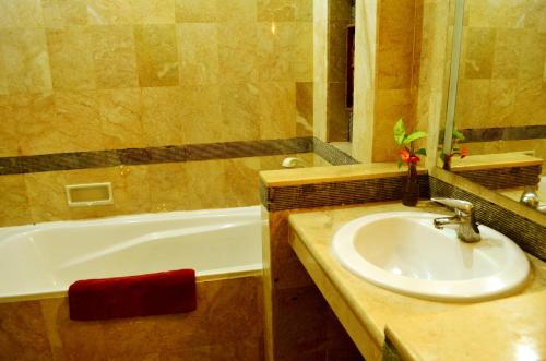 a bathroom with a sink and a bath tub at Nirmala Hotel & Convention Centre in Denpasar