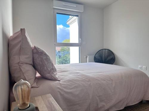 ein Schlafzimmer mit einem Bett mit Kissen und einem Fenster in der Unterkunft Neuf-Lumineux-Calme à 18 mn du centre de Paris in Romainville