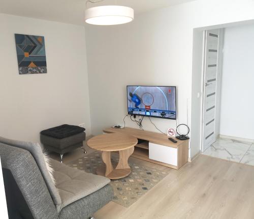 sala de estar con TV, sofá y mesa en Plungės gatvės 18 apartamentai en Telšiai