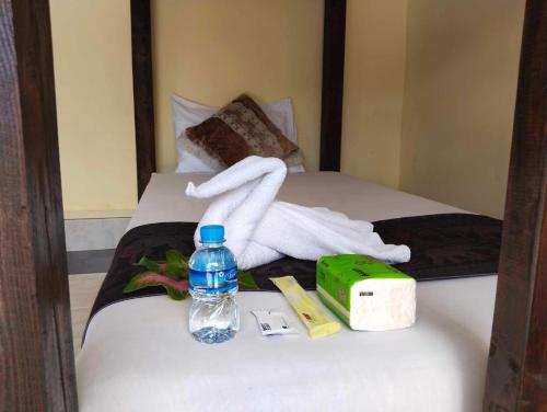 a towel on a bed with a bottle of water at Pakbeng river side in Pakbeng