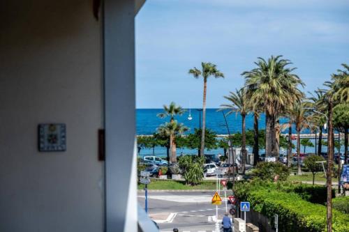 Elle offre une vue sur une rue bordée de palmiers et l'océan. dans l'établissement Magnificent apartment close to the beach with sea view, à Antibes
