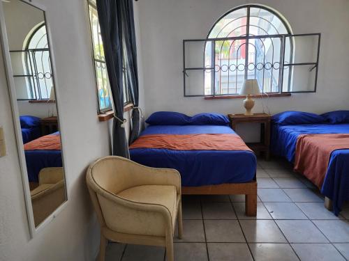 een slaapkamer met 2 bedden, een stoel en een spiegel bij Casa Marina in Puerto Vallarta
