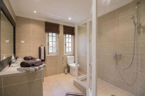 een badkamer met een douche, een wastafel en een toilet bij Villa Caravela in Almancil