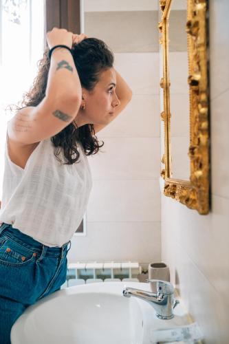 a woman standing in front of a bathroom mirror at Locanda del Musso con Ristorante in Adria