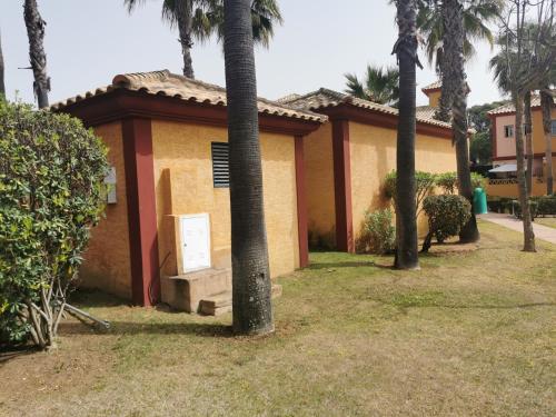 a building with palm trees in front of it at Chalet Islantilla "Costa de la Luz" in Lepe
