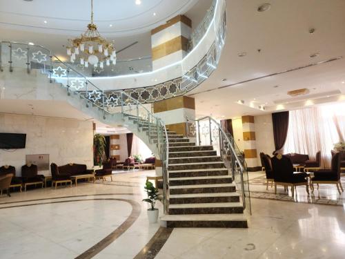 a spiral staircase in a hotel lobby with chairs at فندق إي دبليو جي العزيزية in Makkah