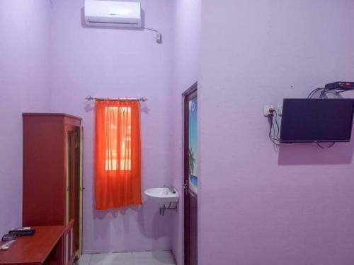 ein Bad mit einem Waschbecken und einem TV an der Wand in der Unterkunft HOME STAY HARAPAN 