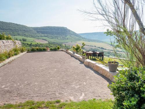 a large gravel driveway with two benches and mountains in the background at Appartement vue panoramique 2 personnes Horizon in Millau