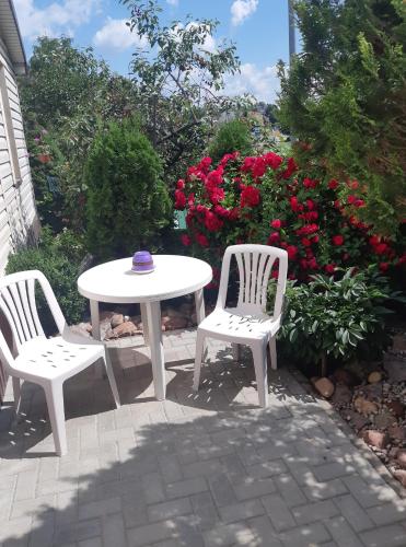a white table and two chairs and a table and flowers at Plungės gatvės 18 apartamentai in Telšiai