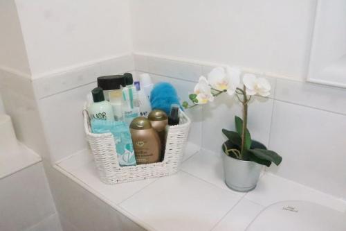 a bathroom counter with a basket of toiletries and a flower at Snug 2BR Apt. Free Parking, 4KTV in London